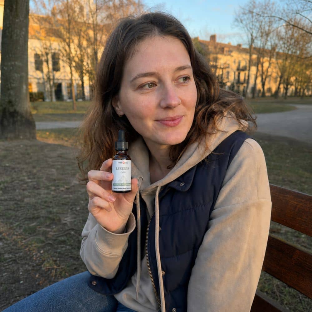 Жена държи бутилка CBD масло Lucerne навън в парк