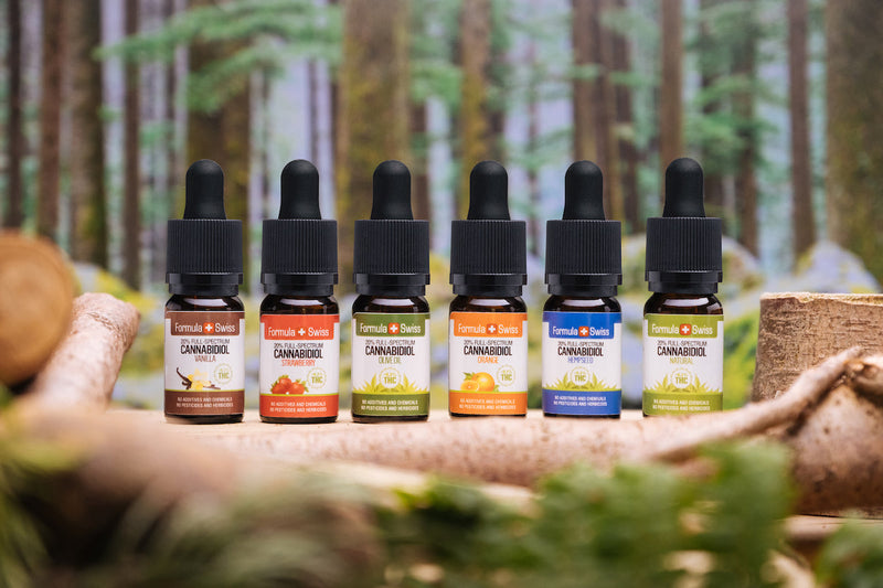 Шест CBD масла с пълен спектър на Formula Swiss в различни масла носители и вкусове пред гора