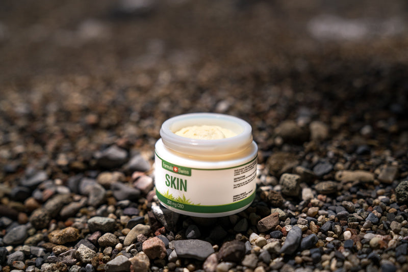 Отворено бурканче балсам CBD Skin на Formula Swiss, 300 mg CBD, на плаж с камъчета