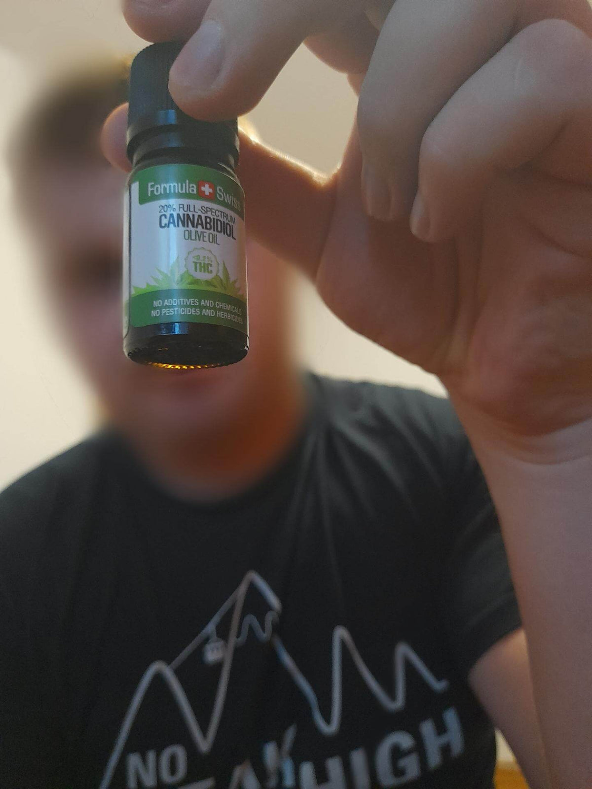 Човек държи продукта: Formula Swiss CBD масло в зехтин